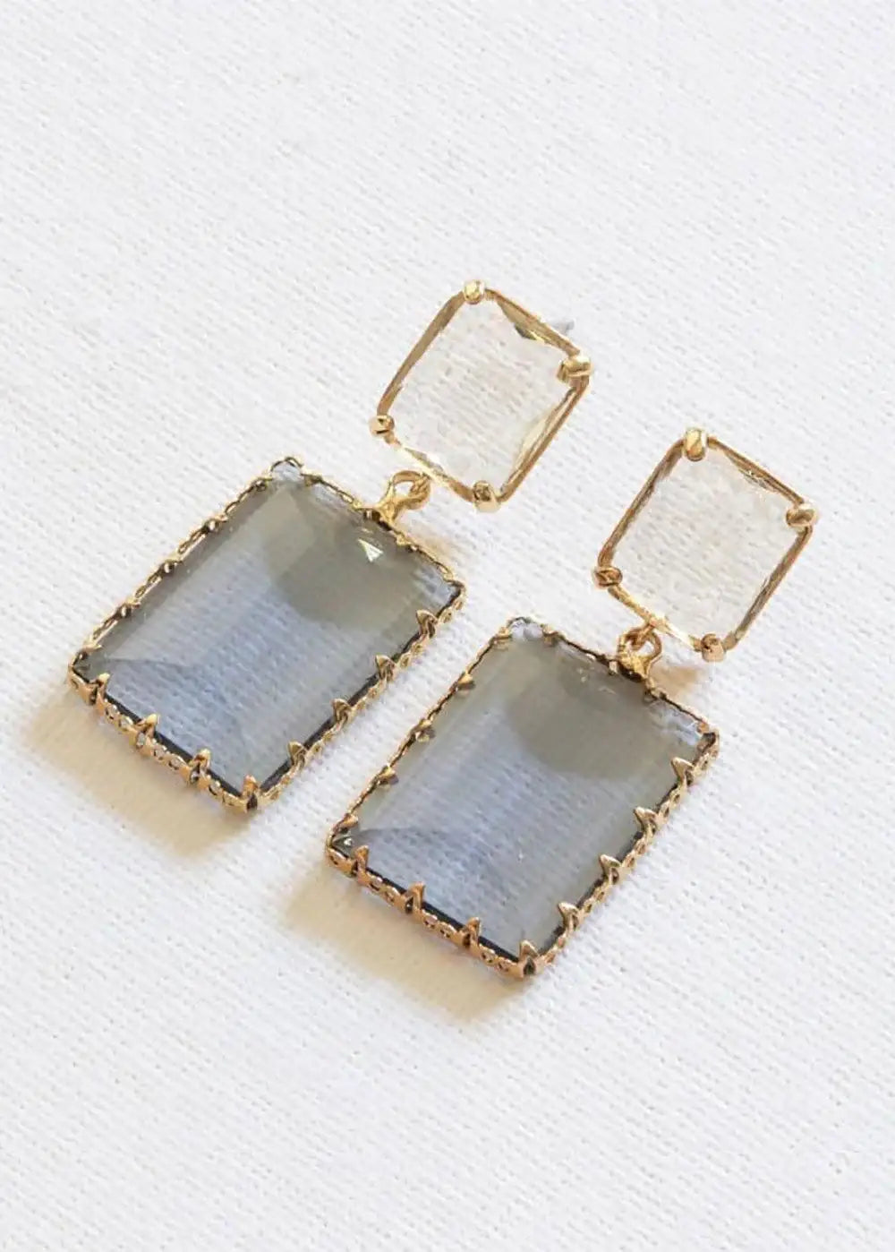 Rectangular blue and clear crystal drop earrings with gold metal prong settings on white background