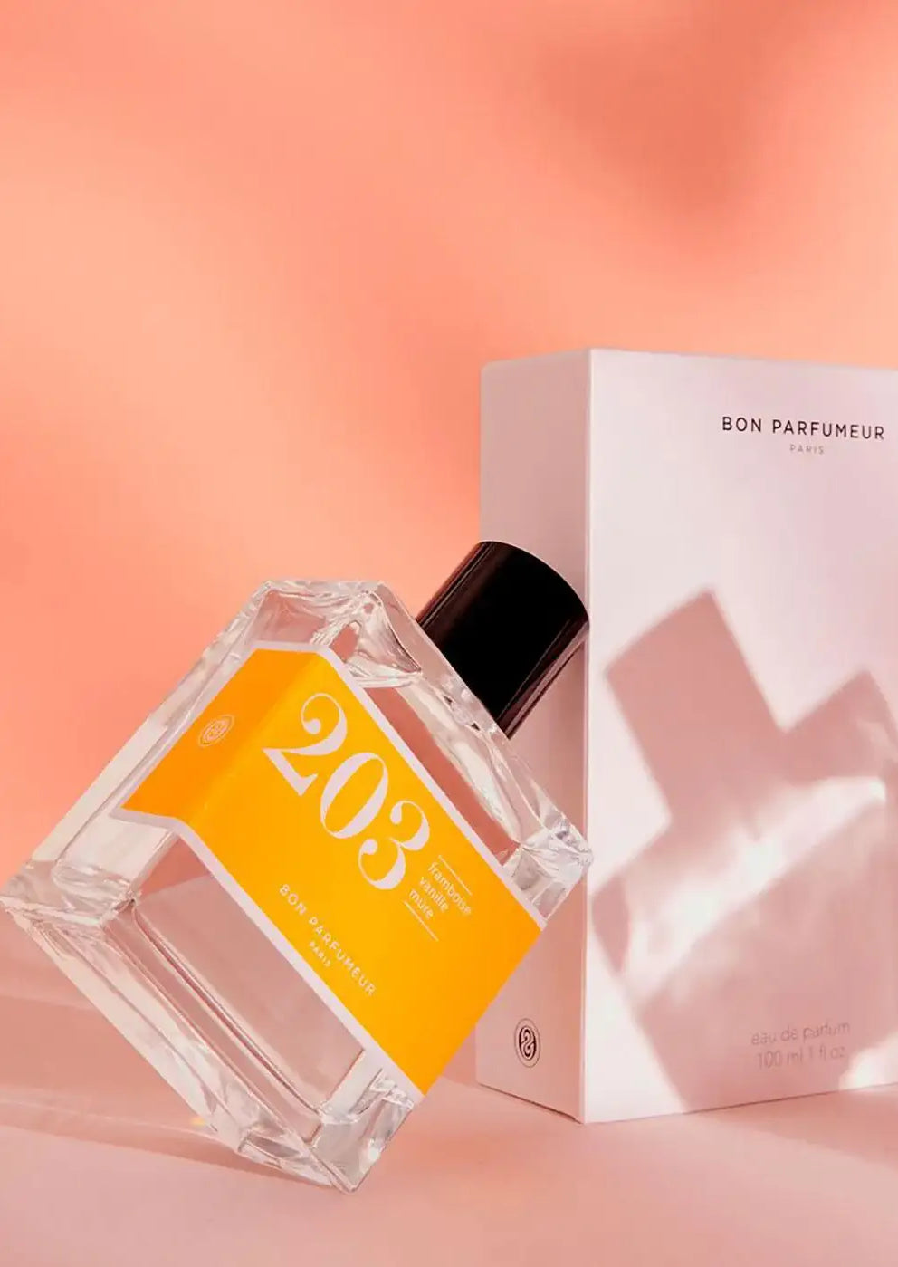 Bon Parfumeur 203 perfume bottle with orange label and box on a peach background