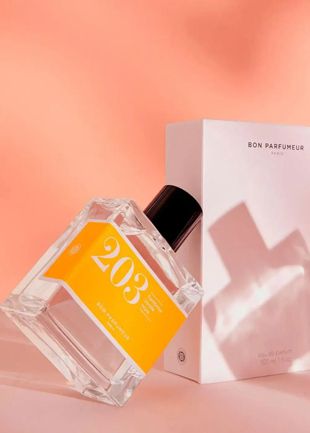 Bon Parfumeur 203 perfume bottle with orange label and box on a peach background