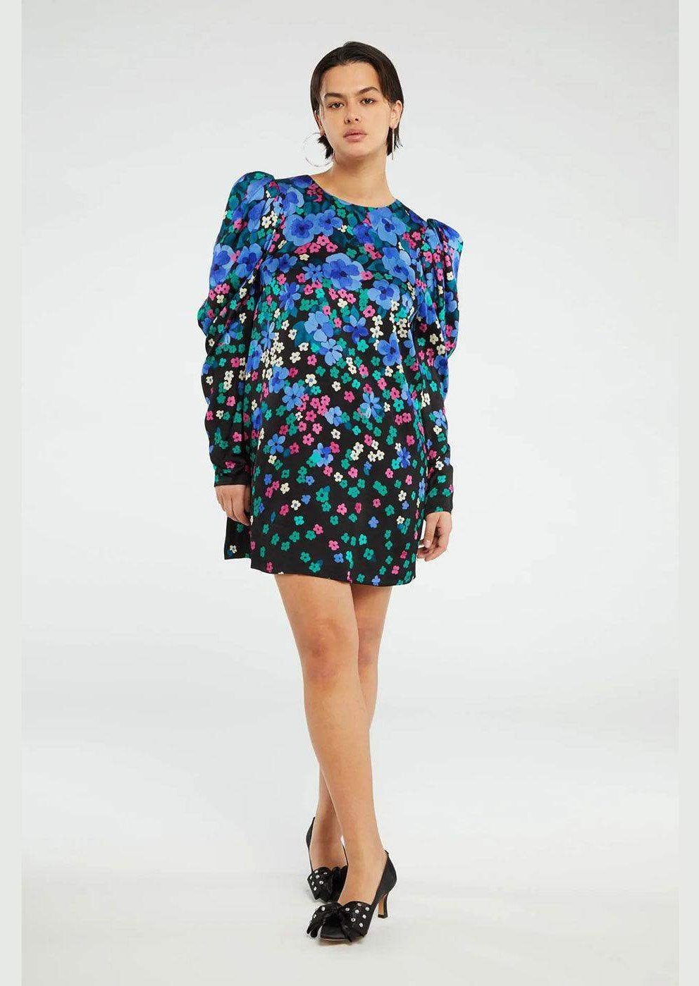 Woman wearing a long sleeve mini dress with bold blue and purple floral print