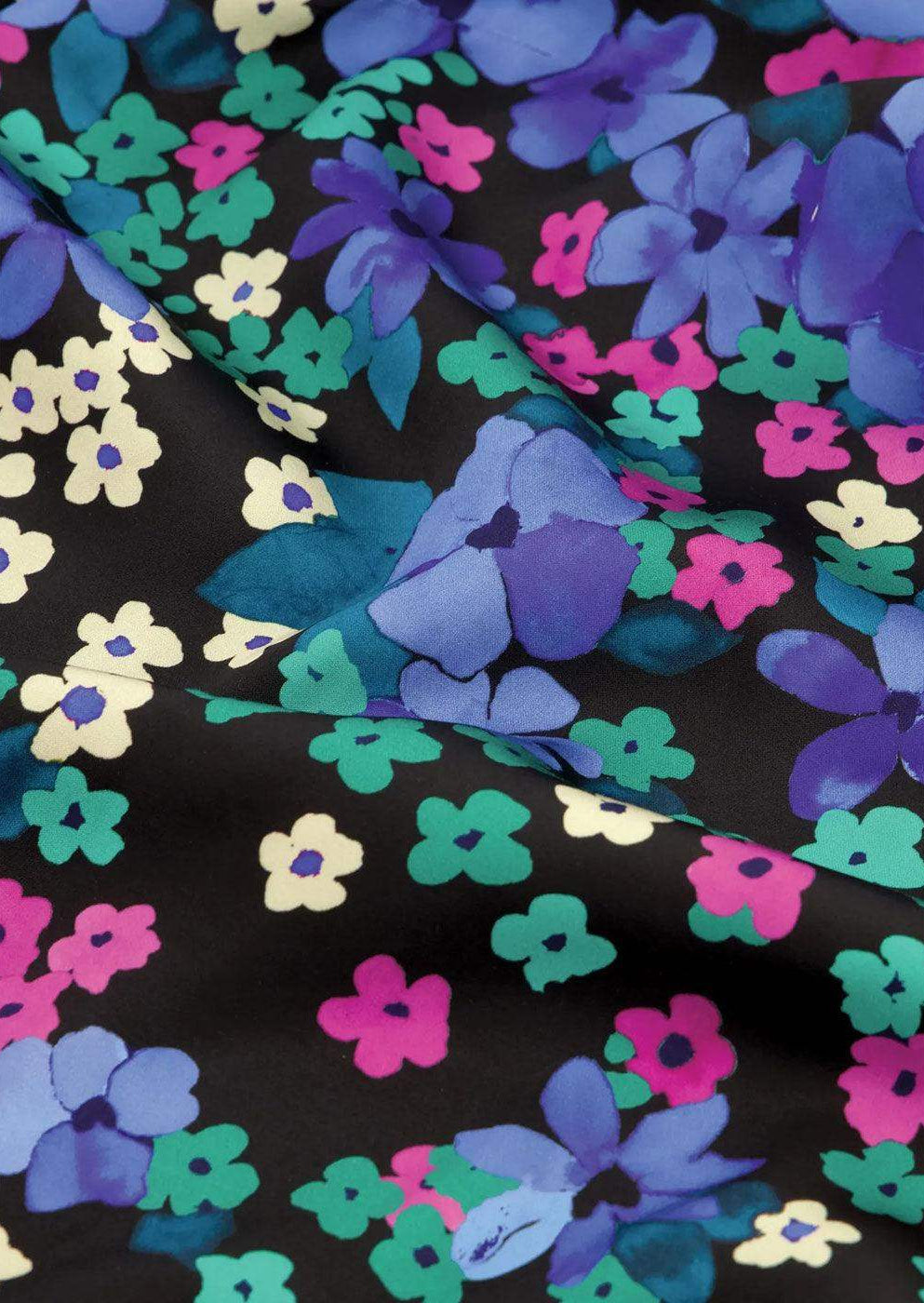 Vibrant floral print fabric with blue, purple, green, and pink flowers on a black background