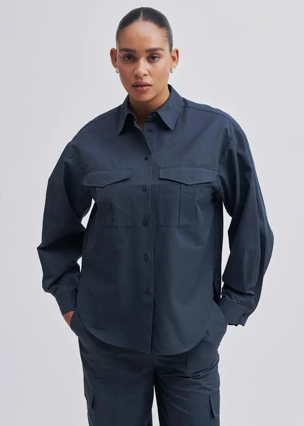 Model wearing a dark navy utility shirt with front pockets and matching trousers