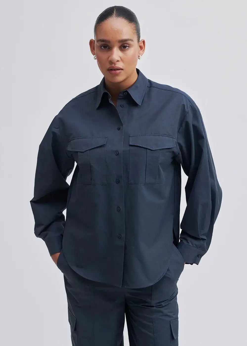 Model wearing a dark navy utility shirt with front pockets and matching trousers