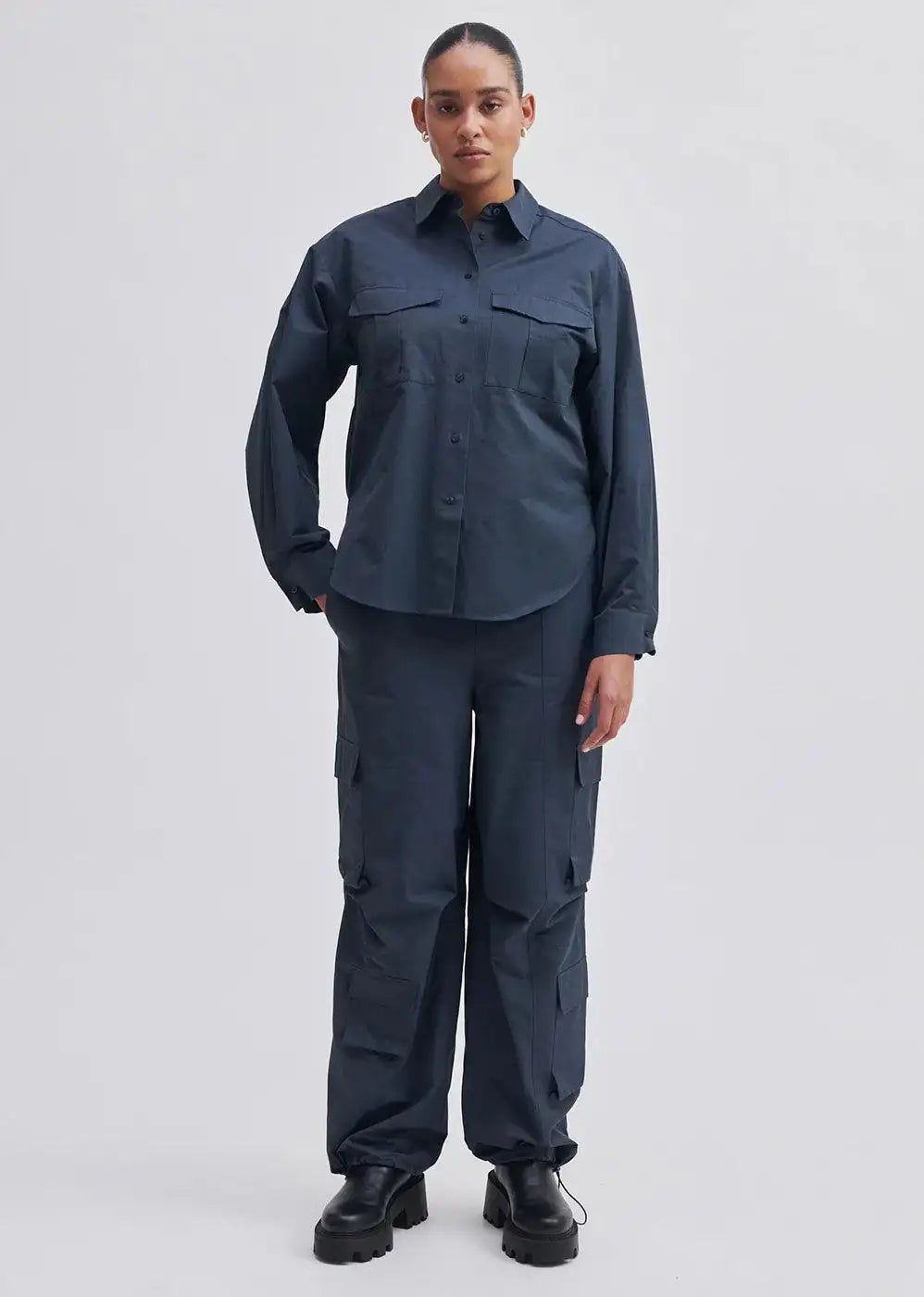Woman modeling navy utility shirt and cargo trousers with patch pockets and black chunky boots