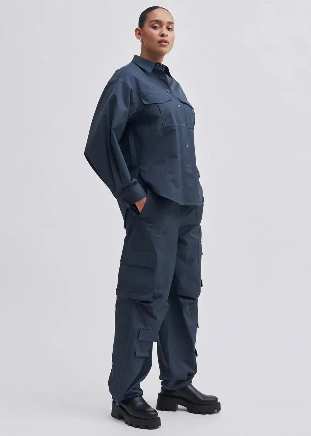 Woman wearing navy blue utility cargo trousers and matching shirt with black boots