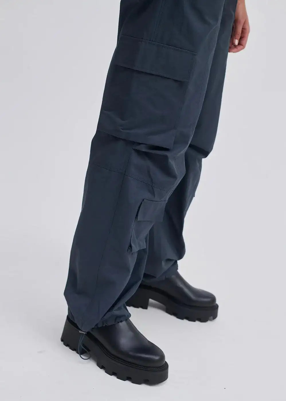 Dark cargo trousers with side pockets and drawstring hem, paired with black chunky boots