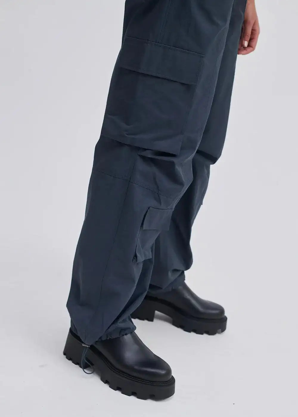 Dark cargo trousers with side pockets and drawstring hem, paired with black chunky boots