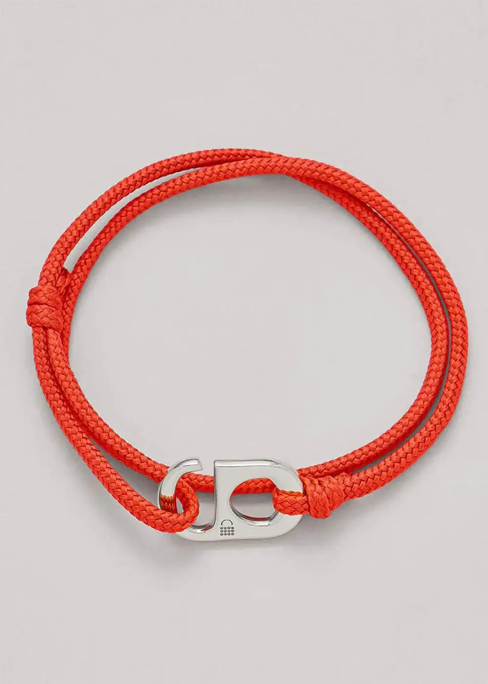 Red braided cord bracelet with silver letter D clasp on grey background