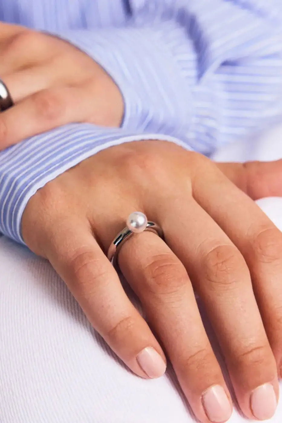 Modern silver ring with a single pearl detail on hand, minimalist jewelry style