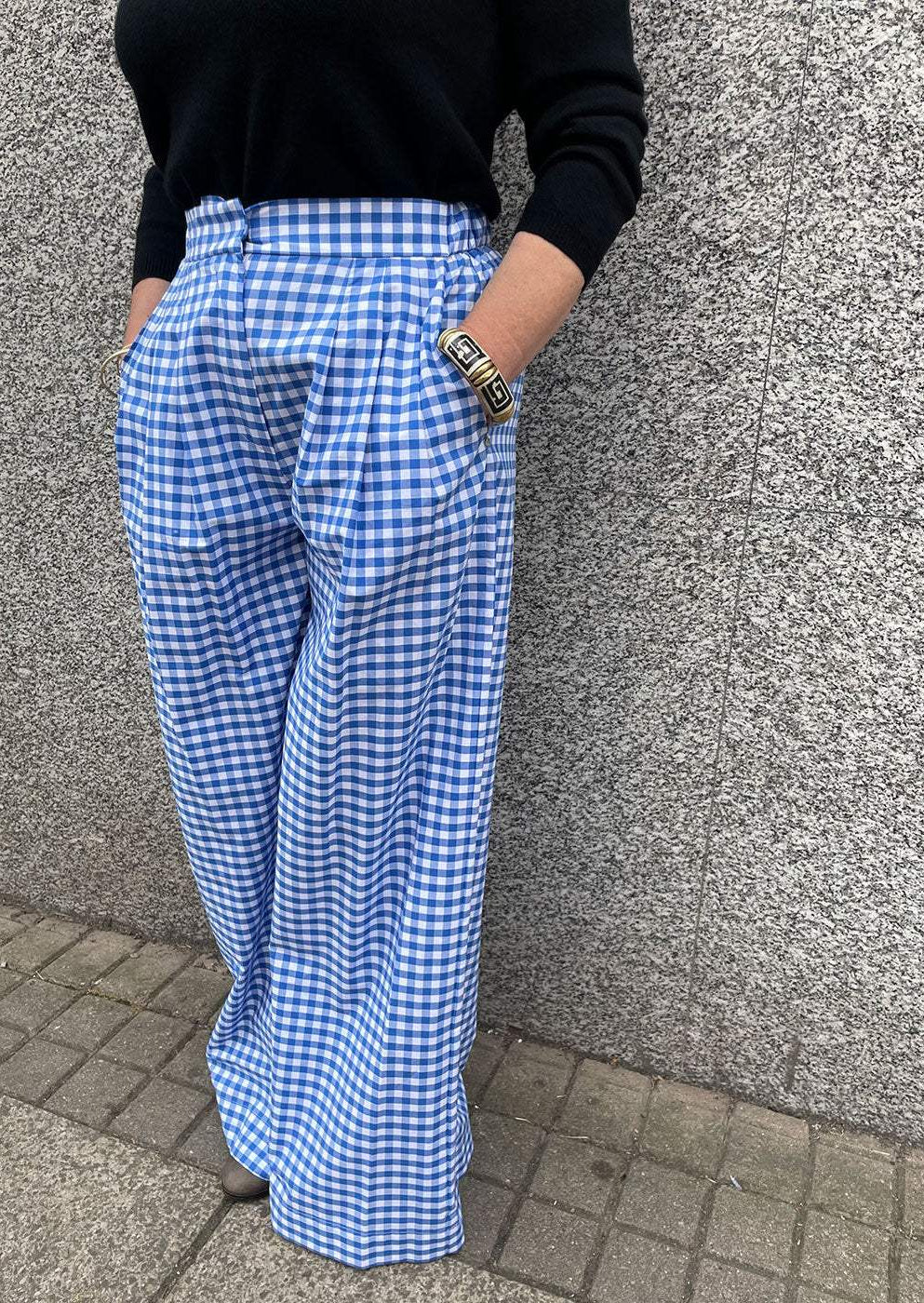 Woman wearing high-waisted blue and white gingham wide-leg trousers and black sweater