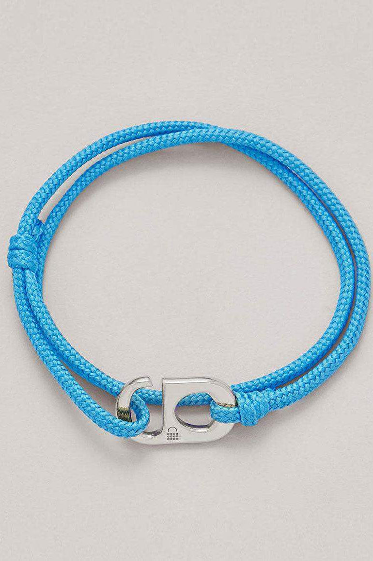 Blue cord bracelet with silver peace charm on neutral background