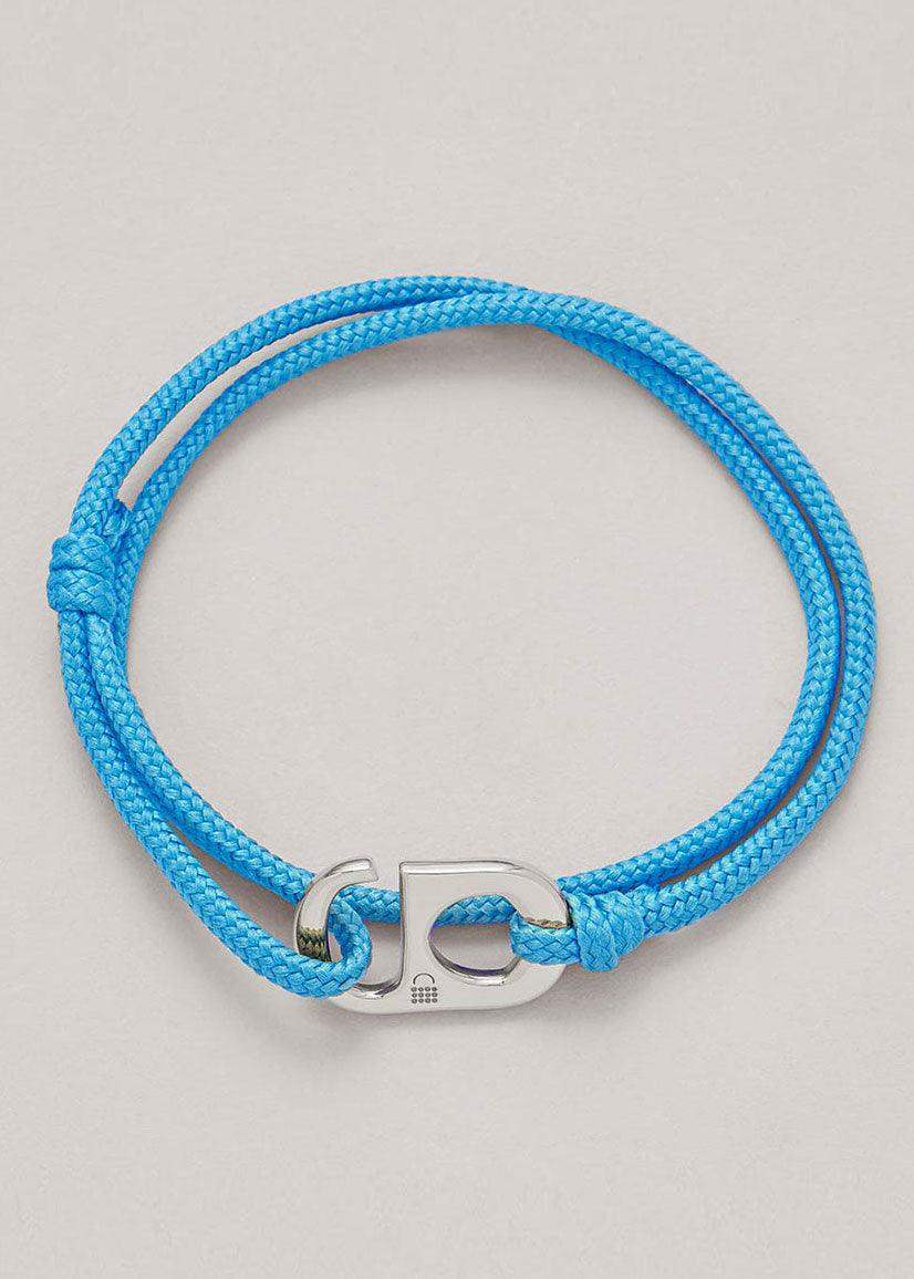 Blue cord bracelet with silver peace charm on neutral background