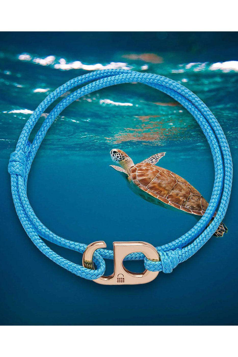 Blue braided bracelet with gold clasp, sea turtle swimming underwater background