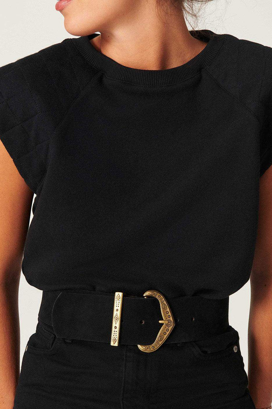 Woman wearing a black suede wide belt with gold engraved buckle over black top and jeans
