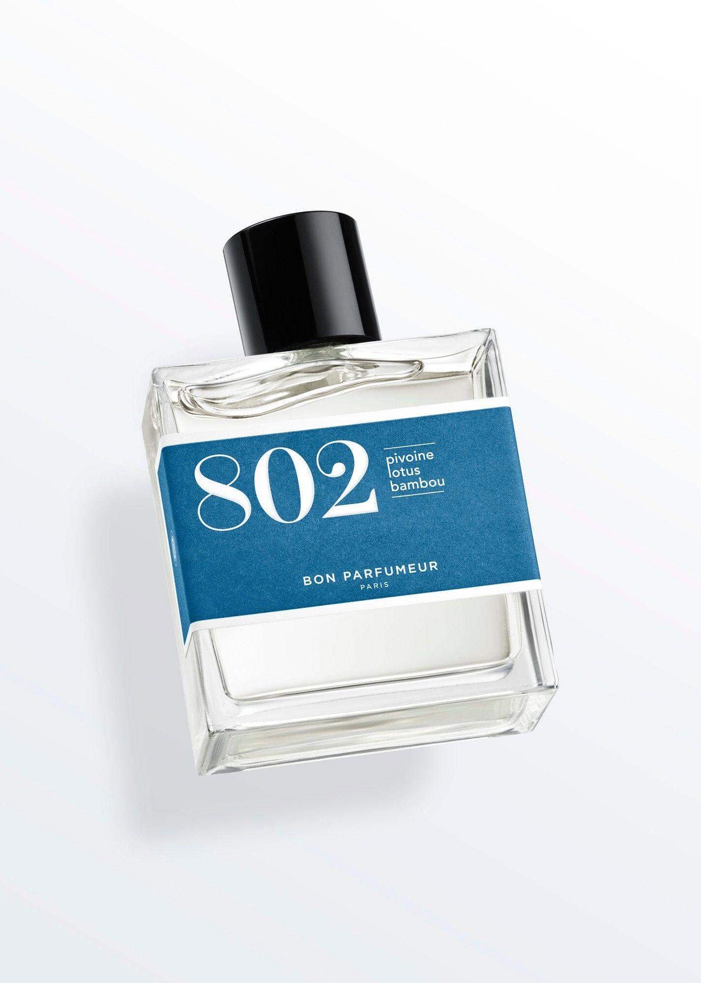 Clear glass perfume bottle with blue label reading '802 pivoine lotus bambou' and black cap