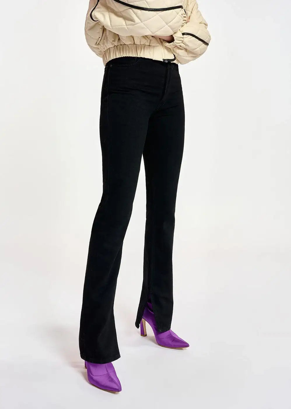 Black straight-leg jeans with front slit detail, styled with purple pointed heels