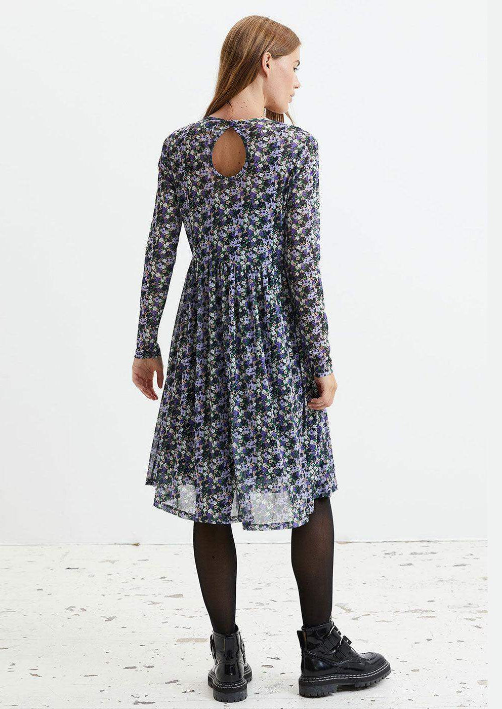 Woman in long sleeve floral print midi dress with back keyhole, black tights and boots