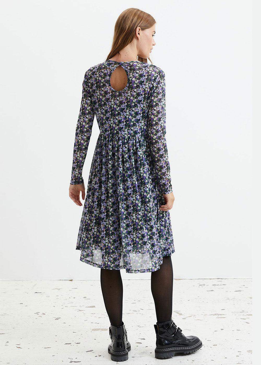 Woman in long sleeve floral print midi dress with back keyhole, black tights and boots