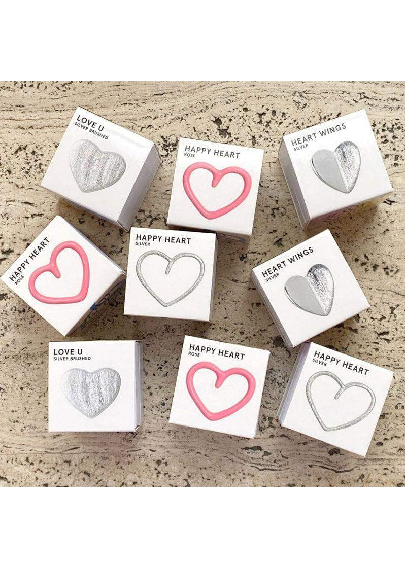 Assorted heart-shaped jewelry boxes labeled Happy Heart, Love U, and Heart Wings on a marble surface.