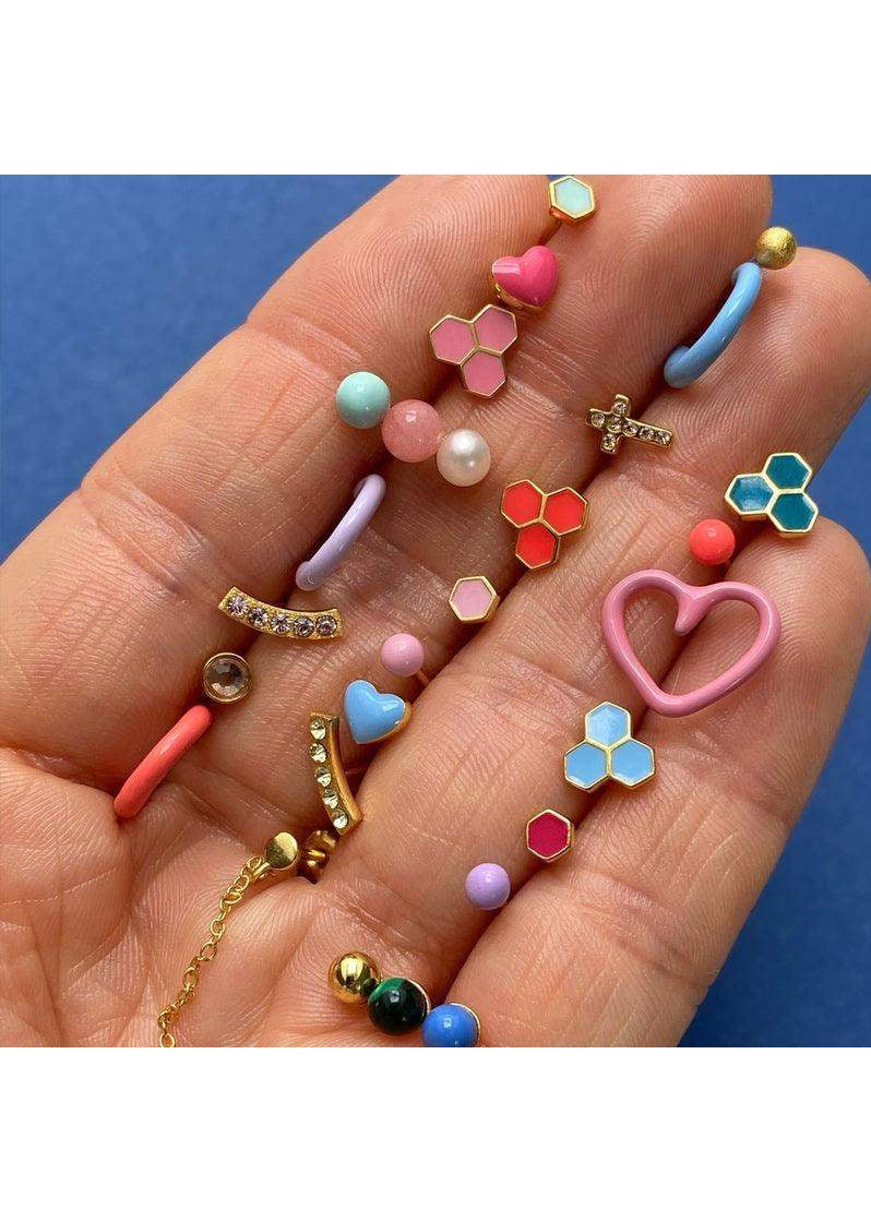 Colorful enamel and gold-tone heart earrings, hexagon studs, and beaded jewelry on hand