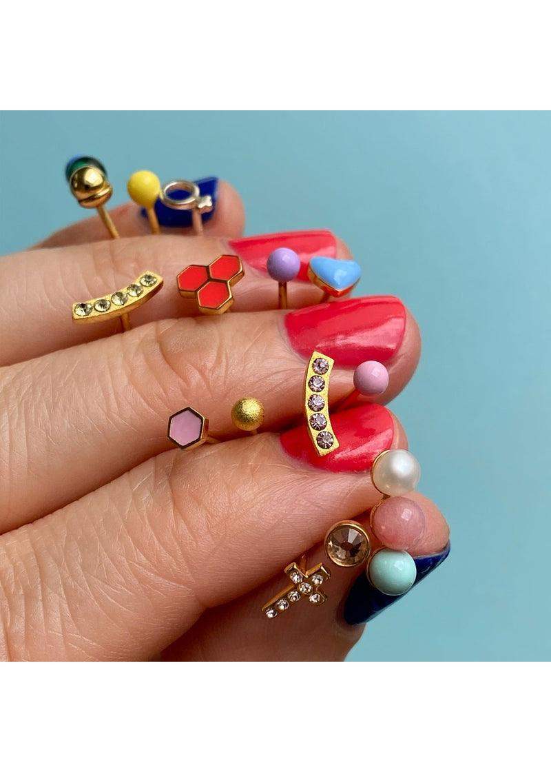 Colorful gold-plated stud earrings in geometric and round shapes displayed on manicured fingers