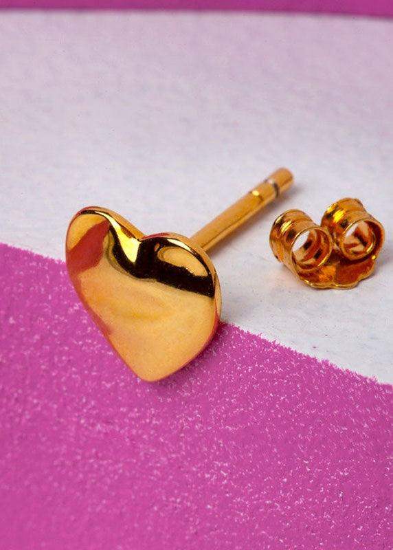 Gold melted heart stud earring with butterfly back on pink and white textured background