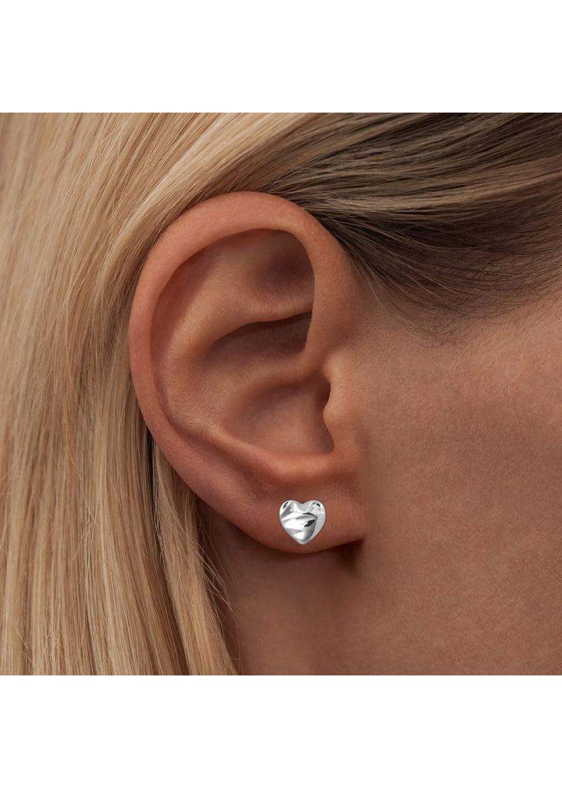 Close-up of a silver melted heart stud earring worn on an ear