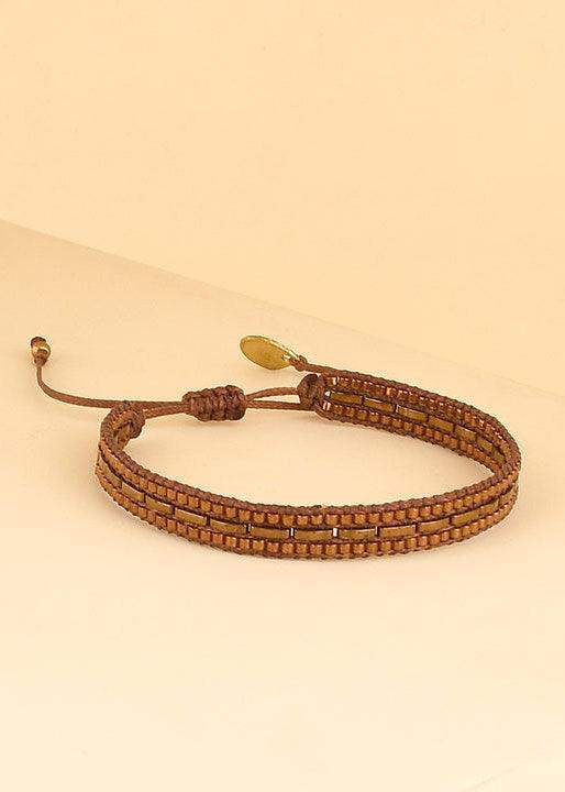 Handmade brown beaded bracelet with adjustable cord and gold accent on neutral background