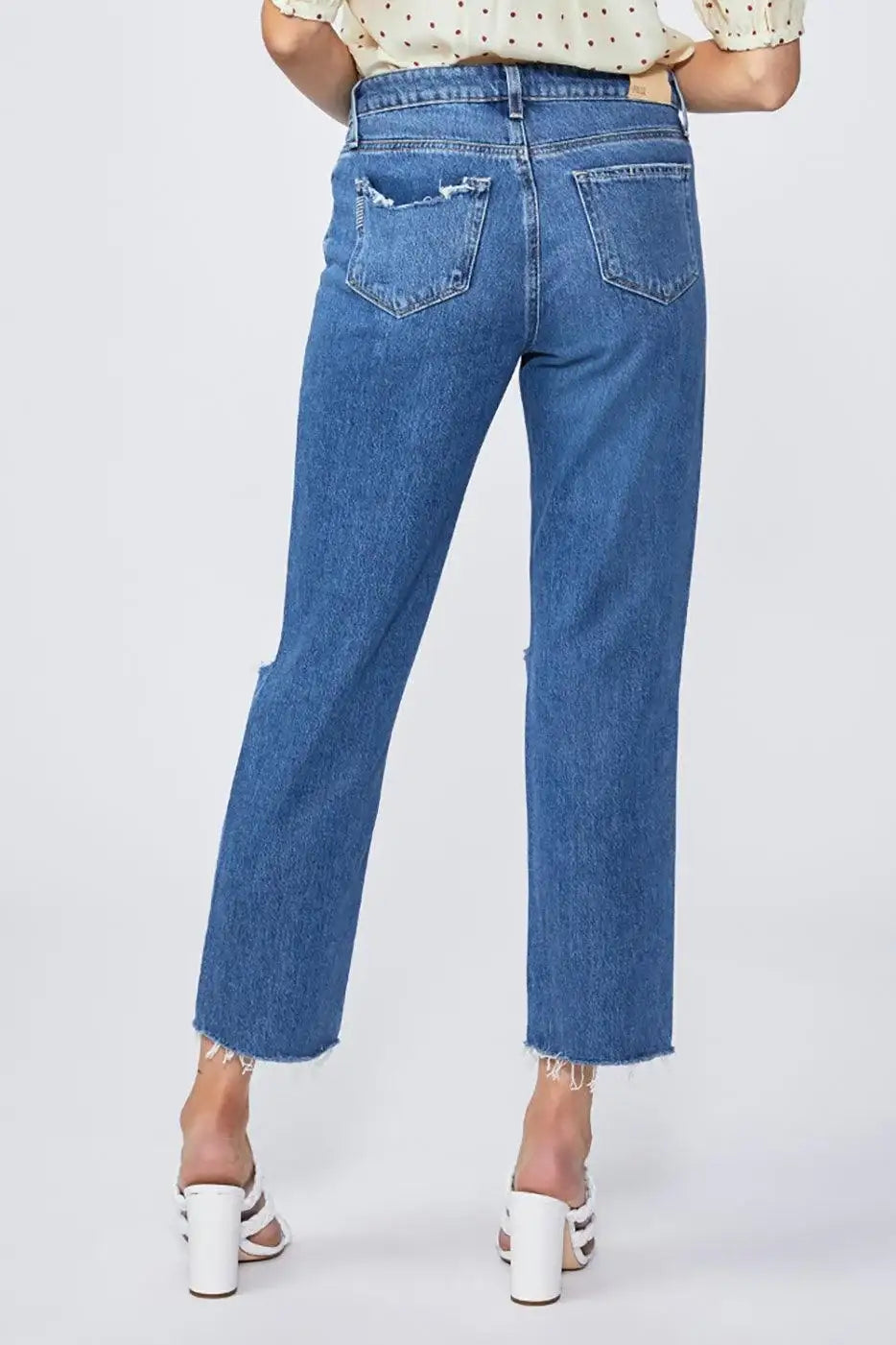 Woman wearing high-waisted straight-leg blue jeans with frayed hems and distressed pockets