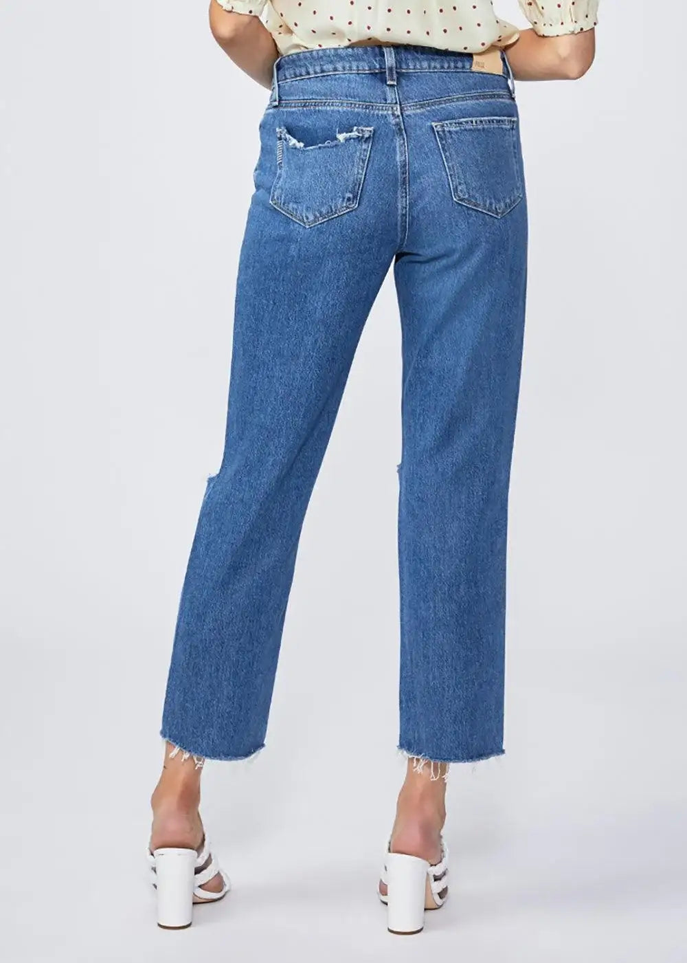 Woman wearing high-waisted straight-leg blue jeans with frayed hems and distressed pockets