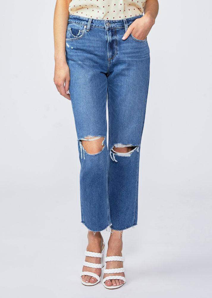 Woman wearing high-waisted straight-leg blue jeans with ripped knees and raw hems.