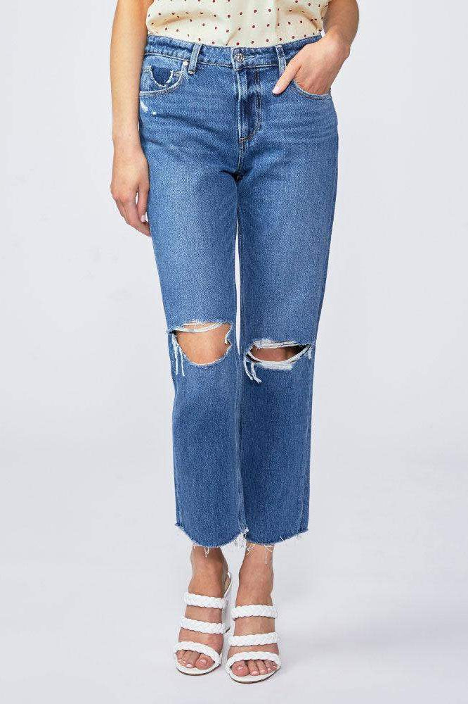 Woman wearing high-waisted straight-leg blue jeans with ripped knees and raw hems.