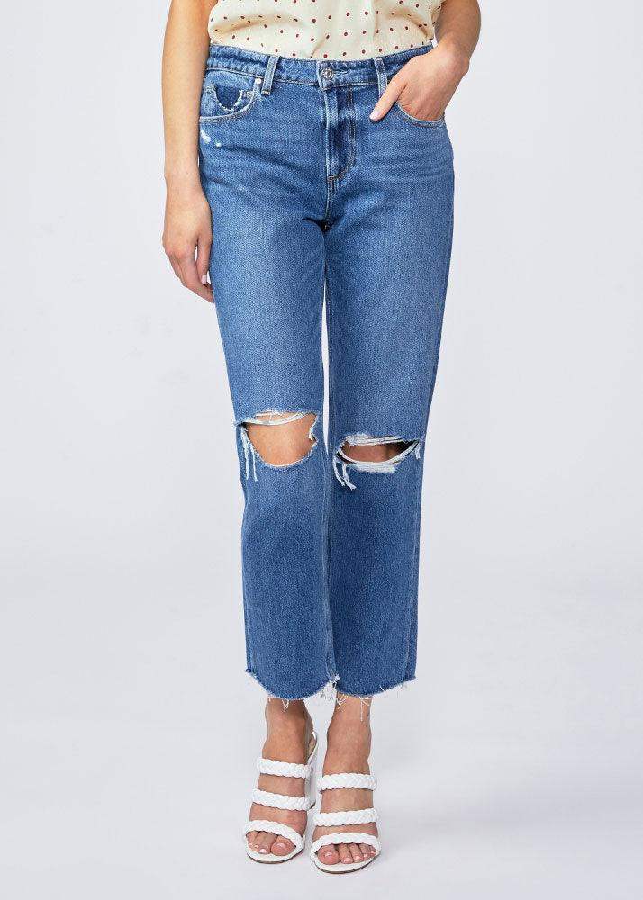 Woman wearing high-waisted straight-leg blue jeans with ripped knees and raw hems.