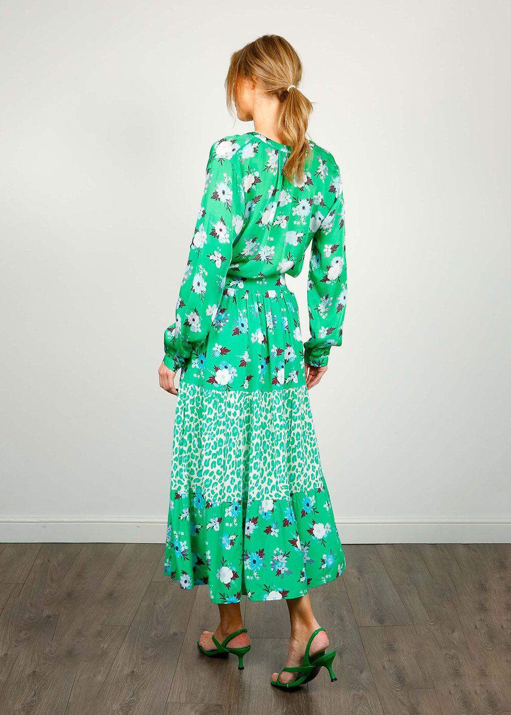 Woman wearing a green floral and animal print midi skirt and blouse, standing indoors