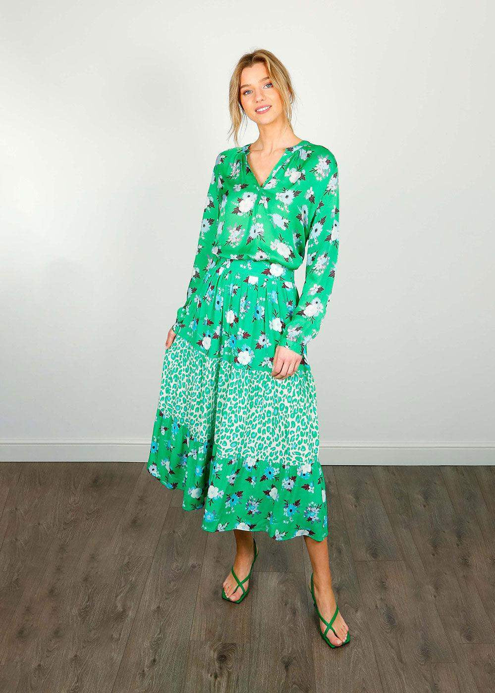 Woman wearing a green floral blouse and matching tiered skirt with leopard print accents