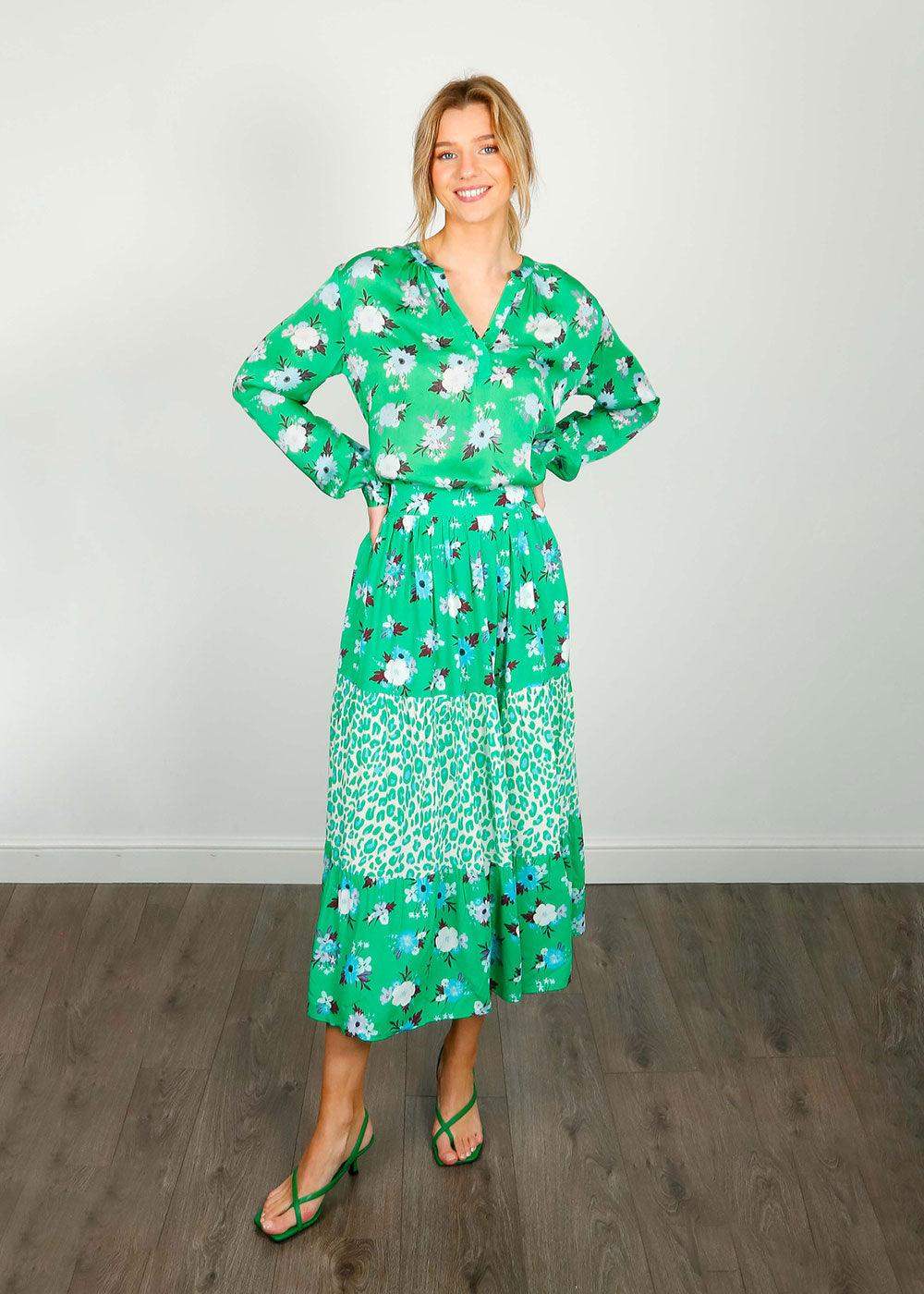 Woman wearing green floral and animal print midi skirt with matching blouse and strappy sandals
