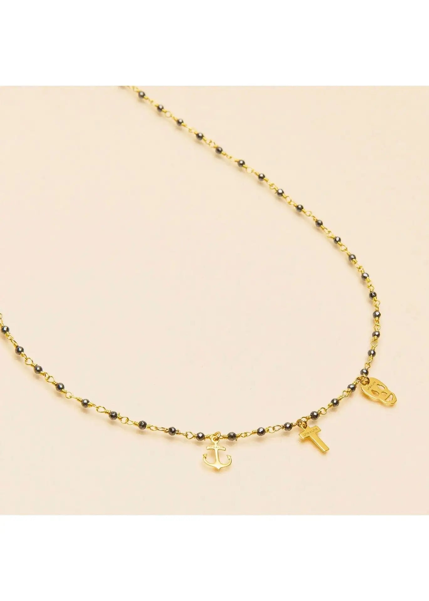 Gold pyrite necklace with anchor, cross, and skull charms on a beaded chain