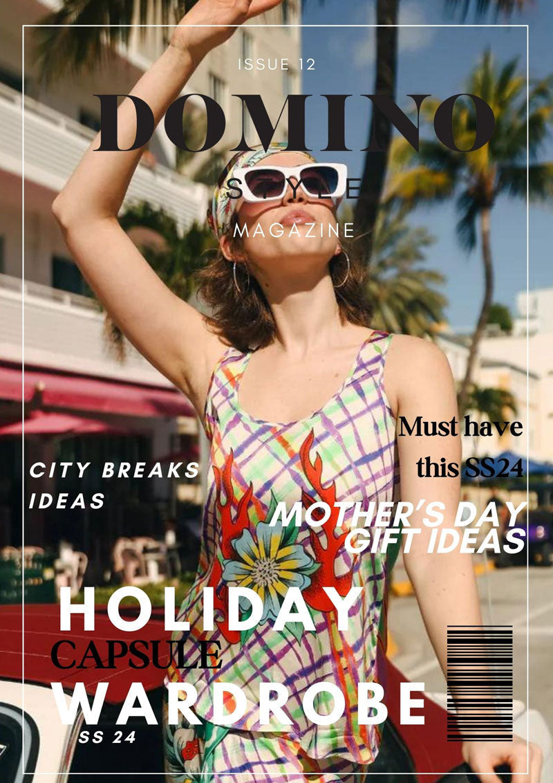 Woman in colorful floral summer dress and sunglasses posing outdoors with palm trees, holiday fashion