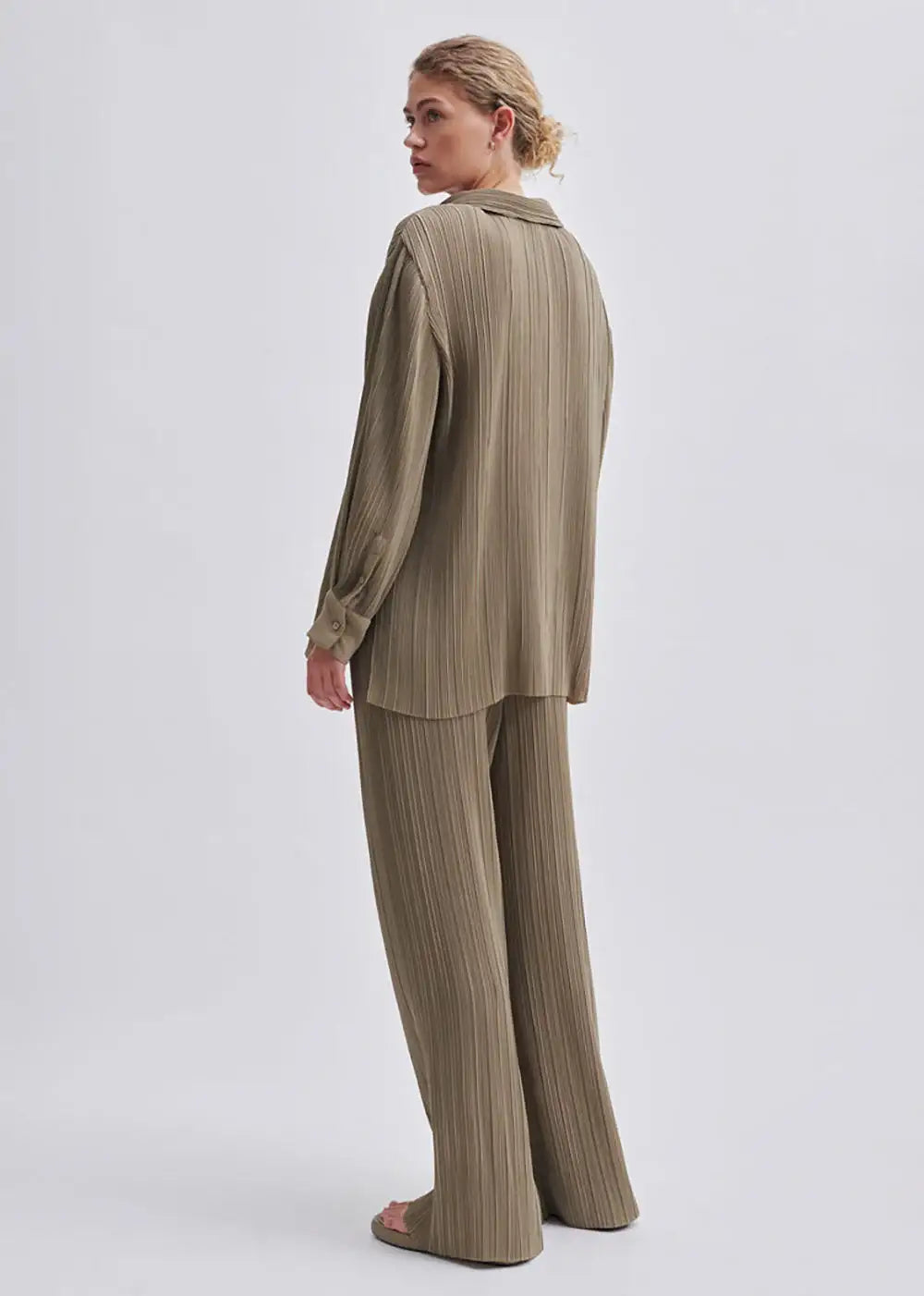 Woman wearing relaxed-fit pleated khaki shirt and wide leg pants set, back view
