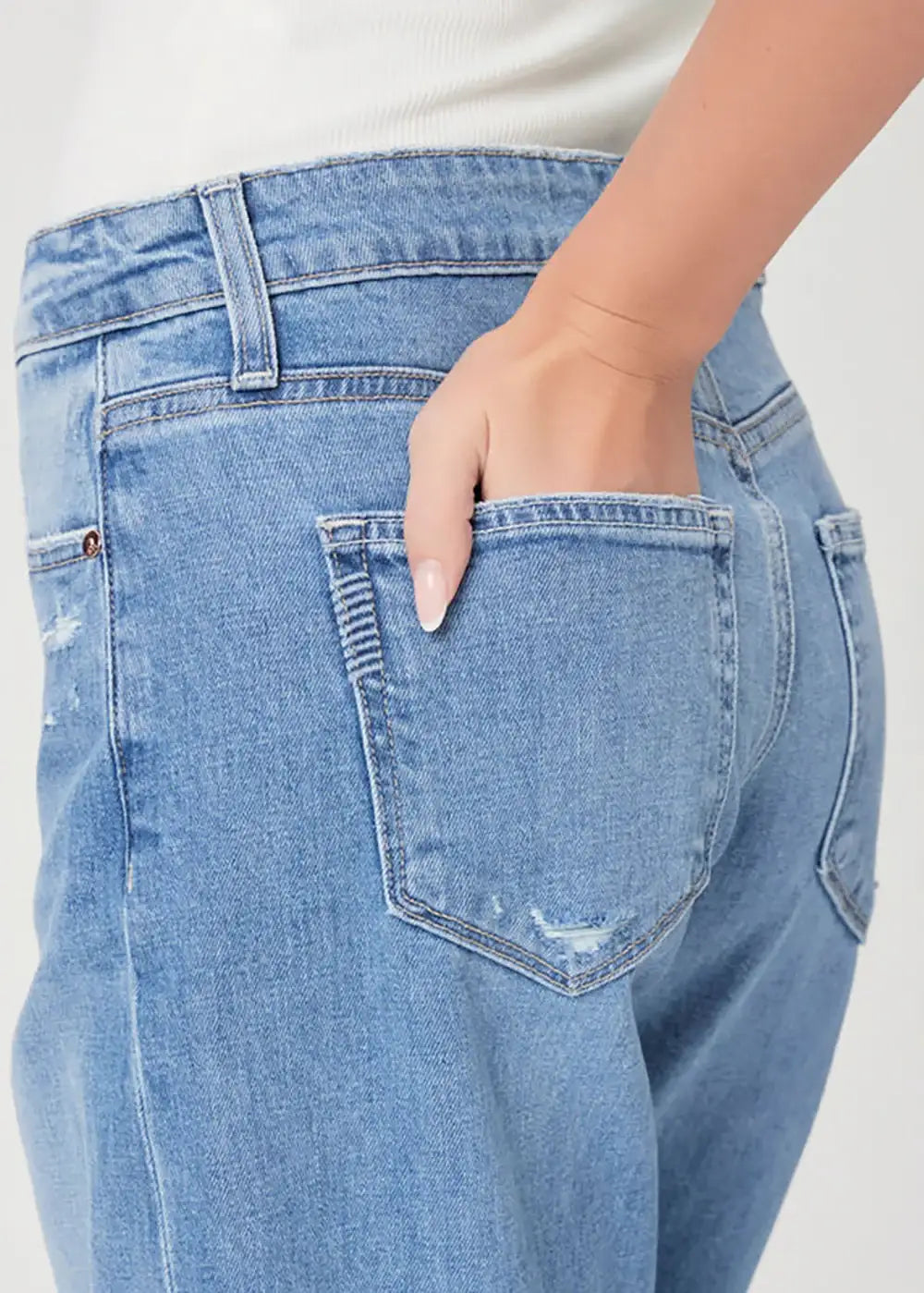 Close-up of light blue high-waisted jeans with hand in back pocket and subtle distressing