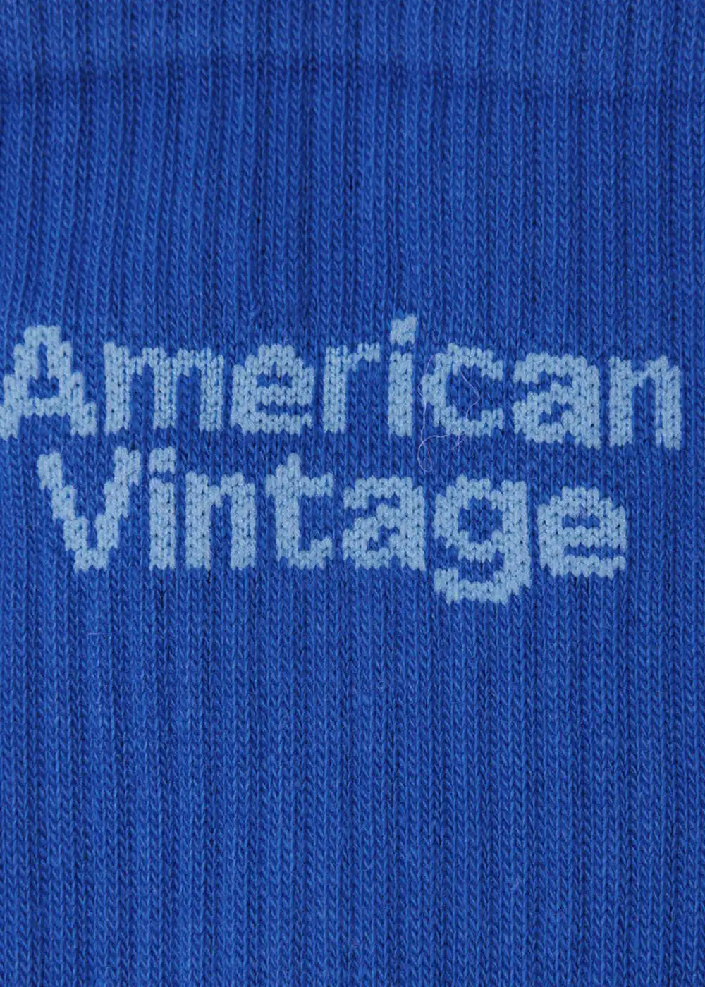 Close-up of blue knitted fabric with 'American Vintage' text in white