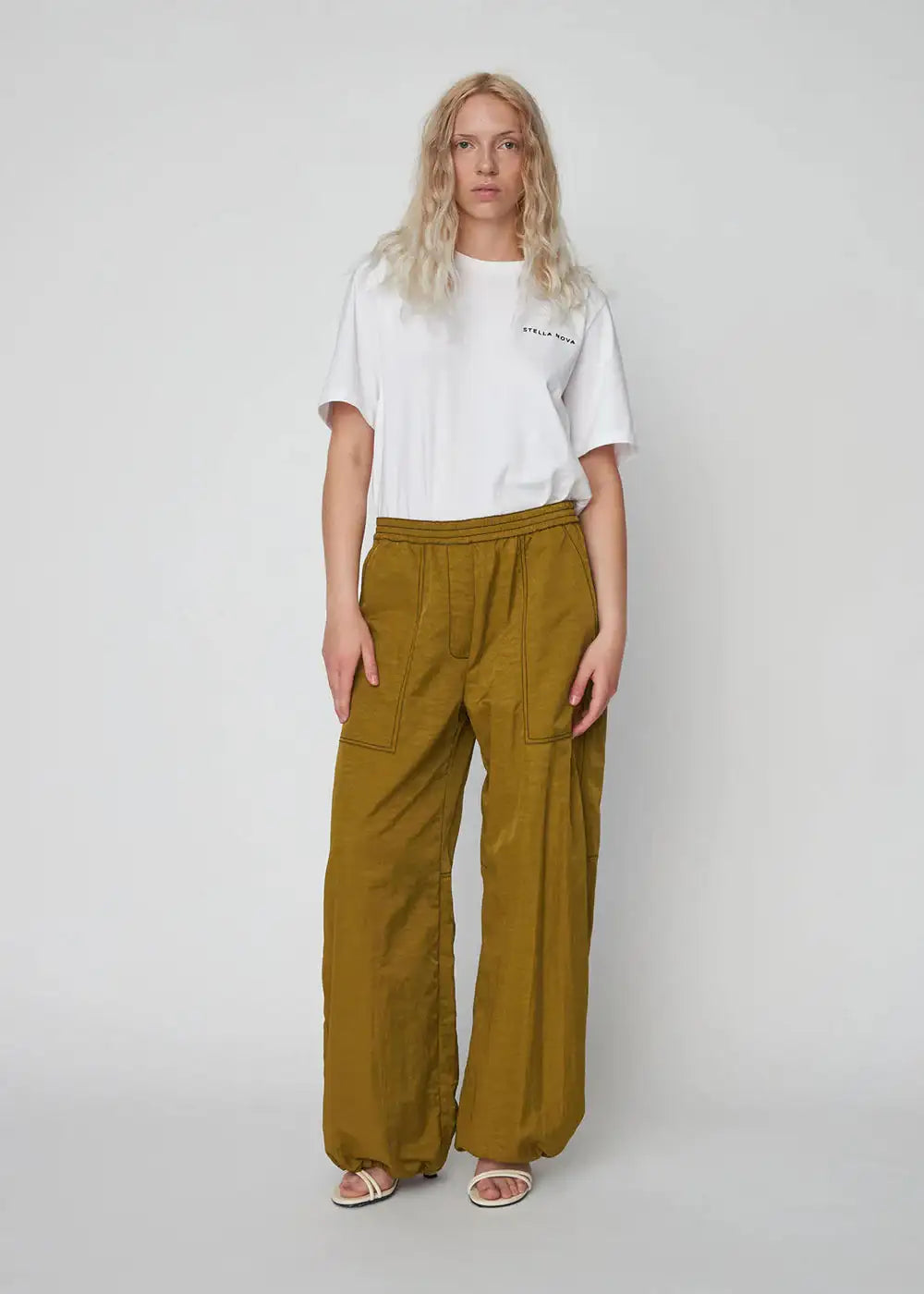 Woman wearing olive green oversized workwear pants with front pockets and a white t-shirt